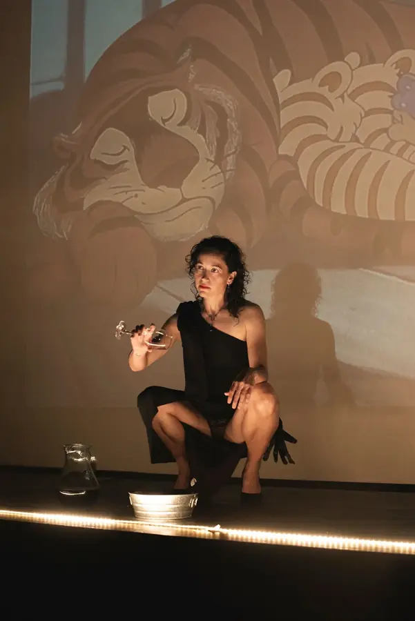 Performance de una artista frente a una proyección de un tigre durante la noche de apertura, Tulum 2025