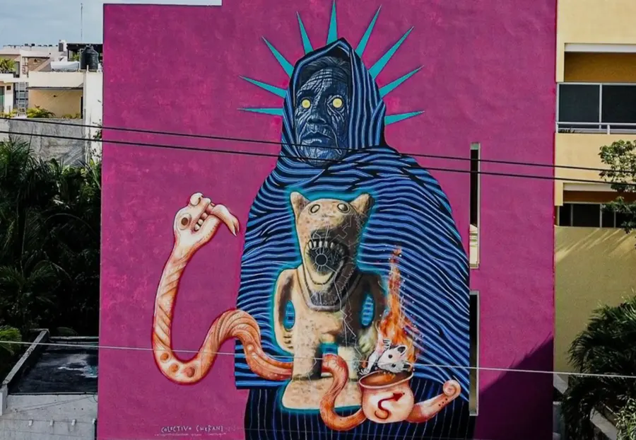 Mural de Colectivo Cherani sobre fachada magenta con figura encapuchada y elementos prehispánicos, Tulum 2025